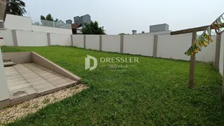 Vista externa de um quintal gramado com muro branco em Lajeado.