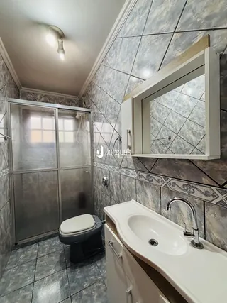 Banheiro com revestimento de azulejos e bancada branca.