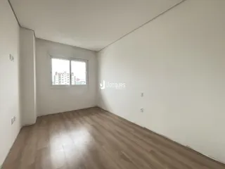 Ambiente interno de uma sala com piso de madeira clara e janela.