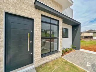 Fachada externa de uma residência em Lajeado, Brasil, com revestimento de pedra e grandes janelas.