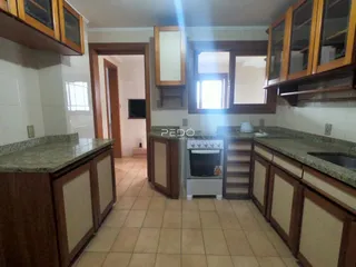 Vista interna de uma cozinha com armários de madeira e bancadas de granito.
