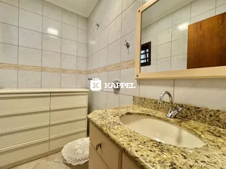 Banheiro com revestimento de azulejos claros e bancada de granito.