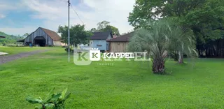 Vista externa de um terreno com gramado verde e árvores.
