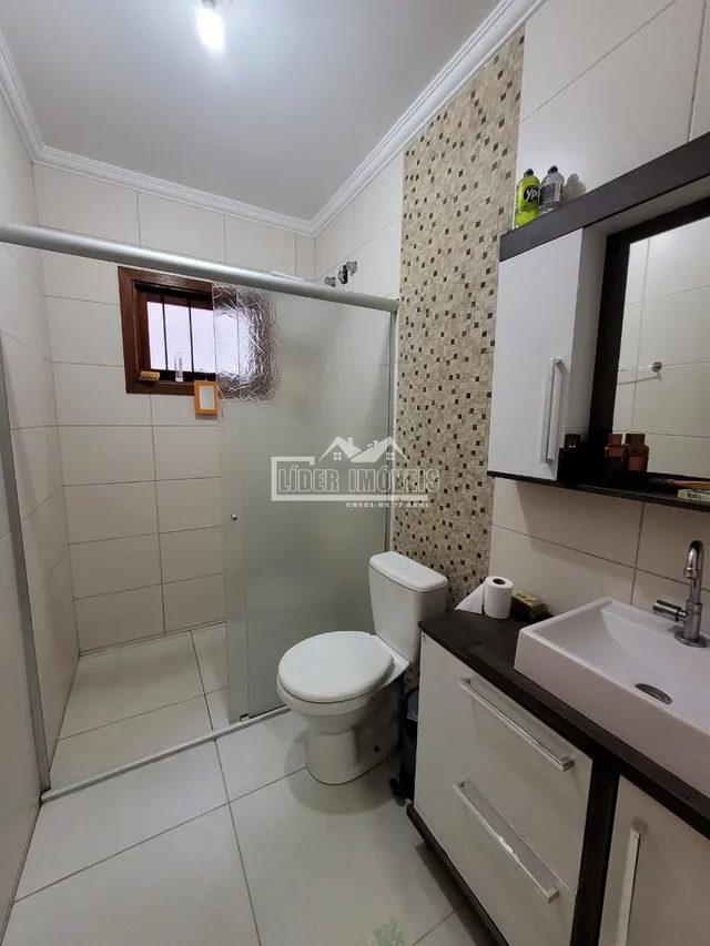 Foto de um banheiro com piso e paredes brancas em uma residência.
