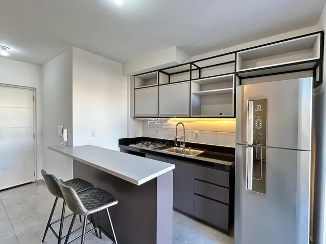 Cozinha moderna com armários escuros e eletrodomésticos de aço inoxidável.