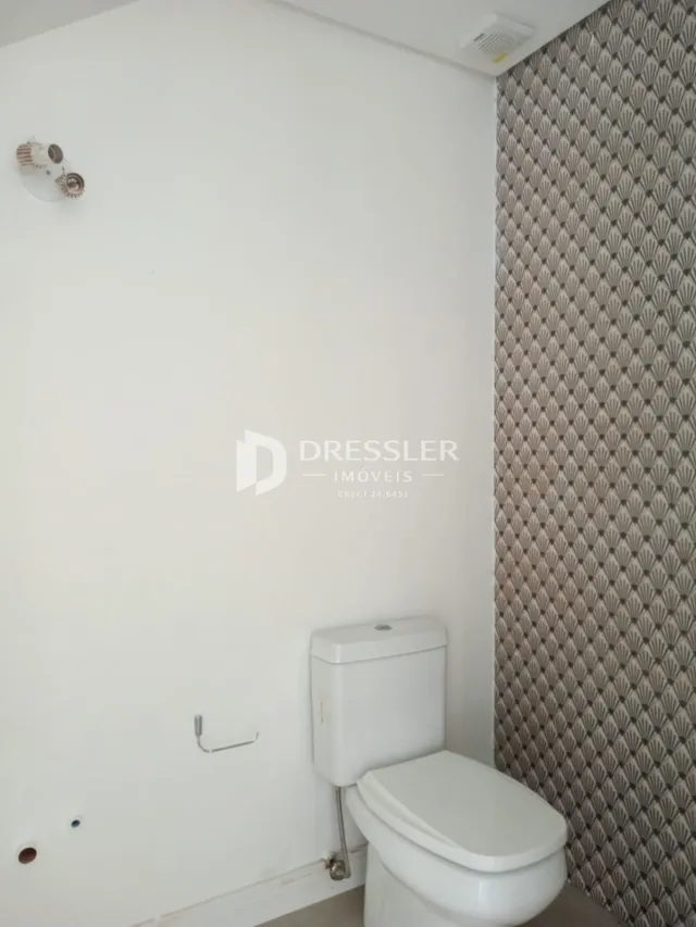 Foto de um ambiente interno mostrando uma parede branca e um vaso sanitário.