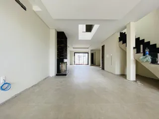 Hall de entrada longo com paredes brancas e piso claro.