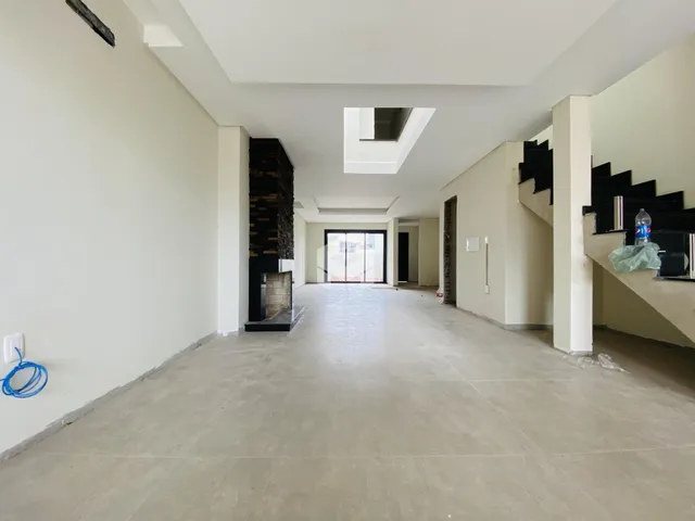 Hall de entrada longo com paredes brancas e piso claro.