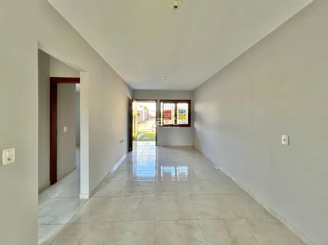 Corredor interno de uma residência com piso de cerâmica clara.