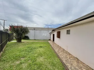 Vista lateral da fachada de uma residência com jardim e calçada.