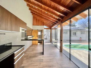 Sala de estar com piso de madeira e portas de vidro que dão acesso ao exterior.