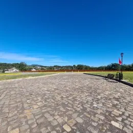 Área externa pavimentada com céu azul.