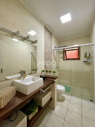 Foto de um banheiro com box de vidro e bancada de madeira.