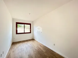 Ambiente interno com piso de madeira e parede branca.