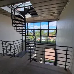 Foto de um corredor com escadaria e guarda-corpo metálico.