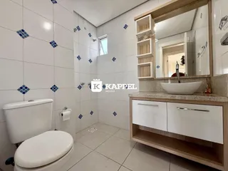 Banheiro com revestimento de azulejos brancos e bancada de madeira.