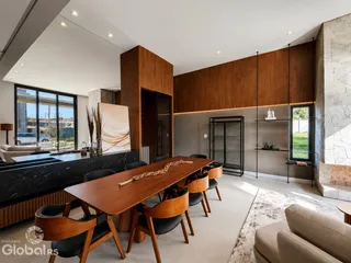 Sala de jantar moderna com mesa de madeira e grandes janelas.