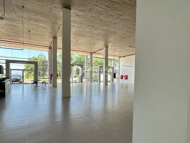 Espaço amplo com teto de concreto aparente e piso claro.