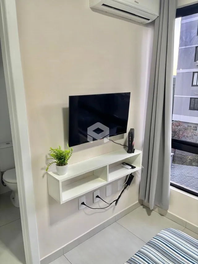 Sala de estar com televisão e janela em um imóvel.