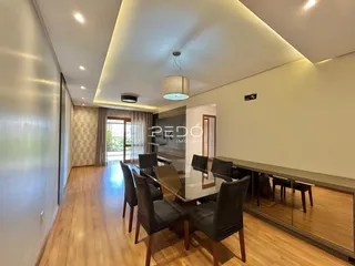 Sala de jantar com piso de madeira e mesa de vidro em um imóvel no Brasil.