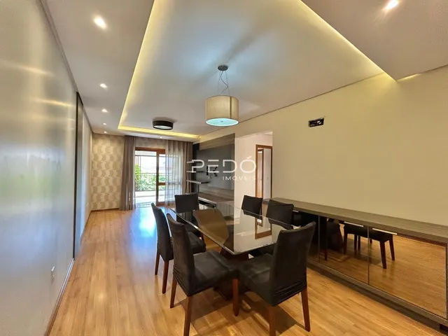 Sala de jantar com piso de madeira e mesa de vidro em um imóvel no Brasil.