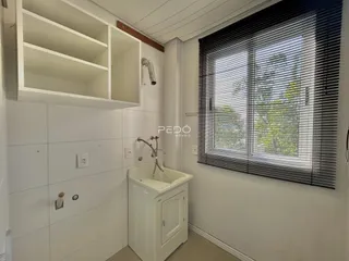 Banheiro com bancada branca e janela.