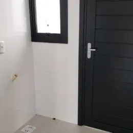 Foto de uma parede branca e uma porta escura em um imóvel.