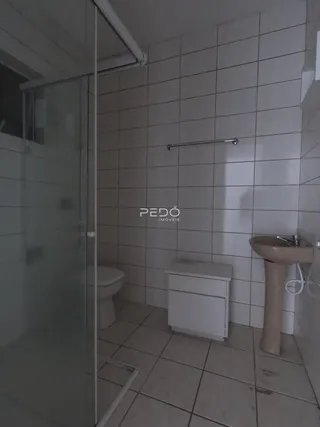 Foto de um banheiro com revestimento cerâmico e box de vidro.