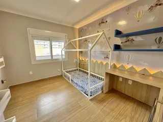 Quarto com cama de ferro branca e piso de madeira em um imóvel no Brasil.