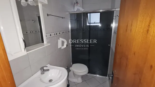 Banheiro com box de vidro e revestimento cerâmico nas paredes.