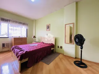 Quarto com cama de madeira e janela em uma residência.