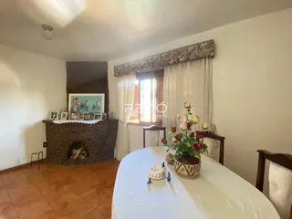 Ambiente interno com lareira de pedra e mesa posta em uma sala.