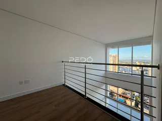 Vista interna de um ambiente com piso de madeira e janela de grande porte.