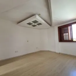 Vista interna de um ambiente com piso de madeira clara e teto branco.
