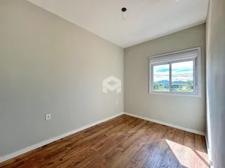 Ambiente interno de uma sala com piso de madeira e janela.
