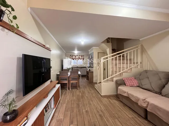 Ambiente interno com piso de madeira e escadaria em uma sala de estar.