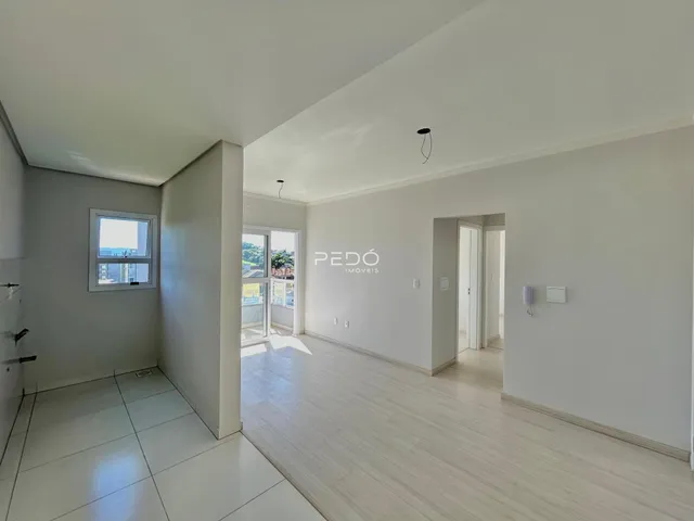 Ambiente interno de uma sala ampla com piso de madeira clara.