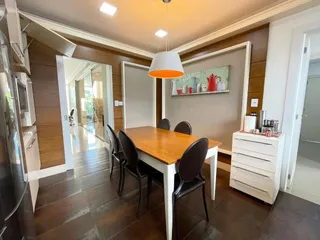 Uma foto de uma sala de jantar com mesa de madeira e cadeiras escuras.