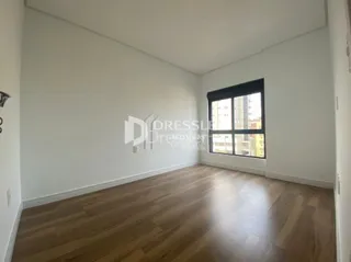 Sala de estar com piso de madeira e grande janela.