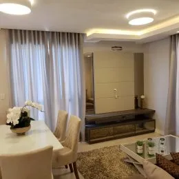 Sala de estar com cortinas claras e iluminação suave.