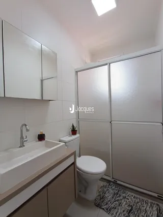 Foto de um banheiro com bancada e armários brancos.