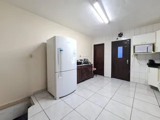 Foto de uma cozinha com geladeira branca e piso de cerâmica clara.