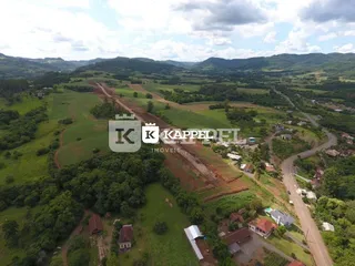 Vista aérea de uma área rural com vegetação verde e colinas.