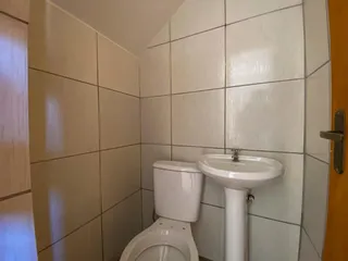 Foto interna de um banheiro com revestimento de azulejos brancos e pia.