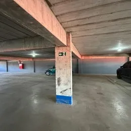 Foto de um espaço interno com piso de concreto e estrutura de vigas exposta.