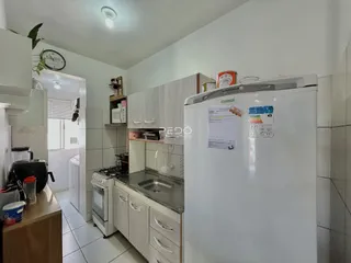 Foto de uma cozinha com armários brancos e piso cerâmico.
