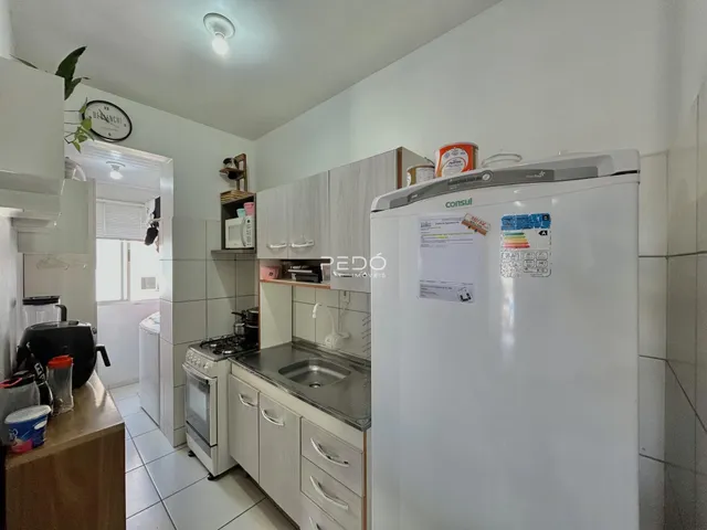 Foto de uma cozinha com armários brancos e piso cerâmico.