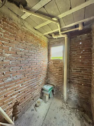 Vista interna de uma parede de tijolos aparentes com tubulações expostas.