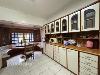 Interior de uma sala de jantar com armários de madeira e janelas.