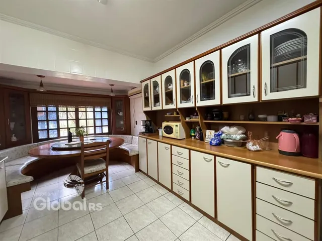 Interior de uma sala de jantar com armários de madeira e janelas.